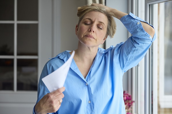 woman fanning herself with a piece of paper