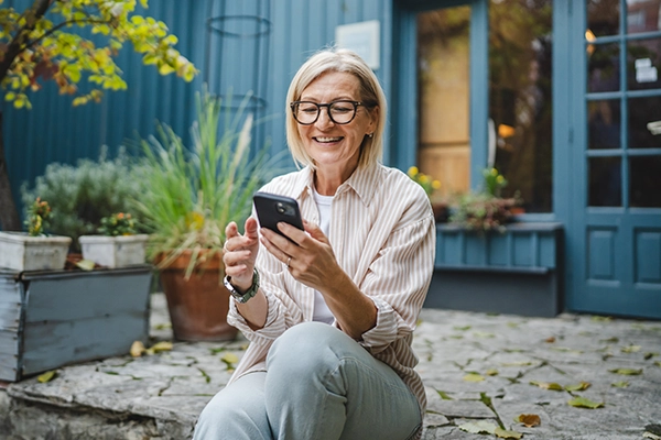 A woman uses her cell phone while sitting on a modern rustic porch