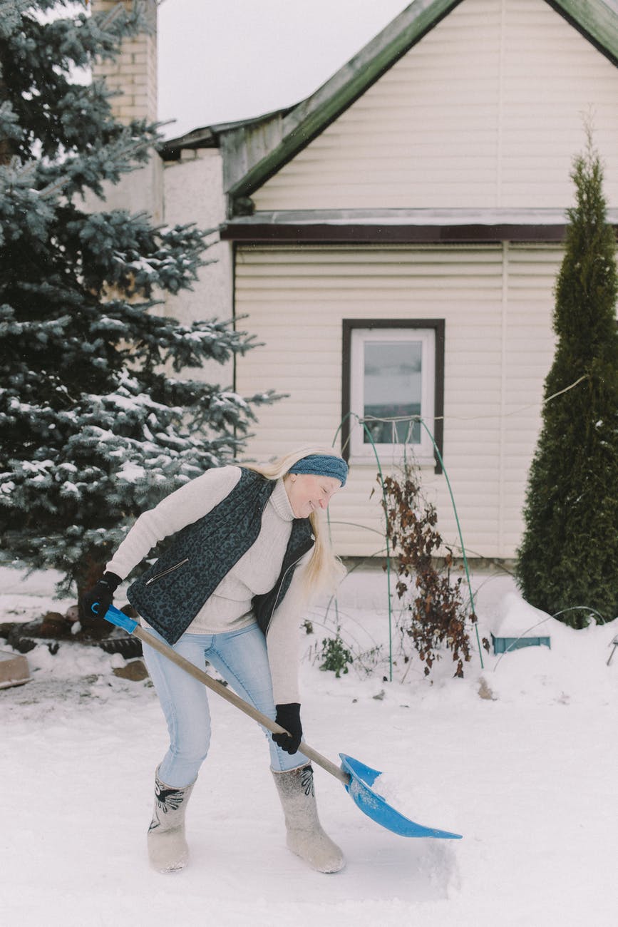 woman scooping snow with shovel