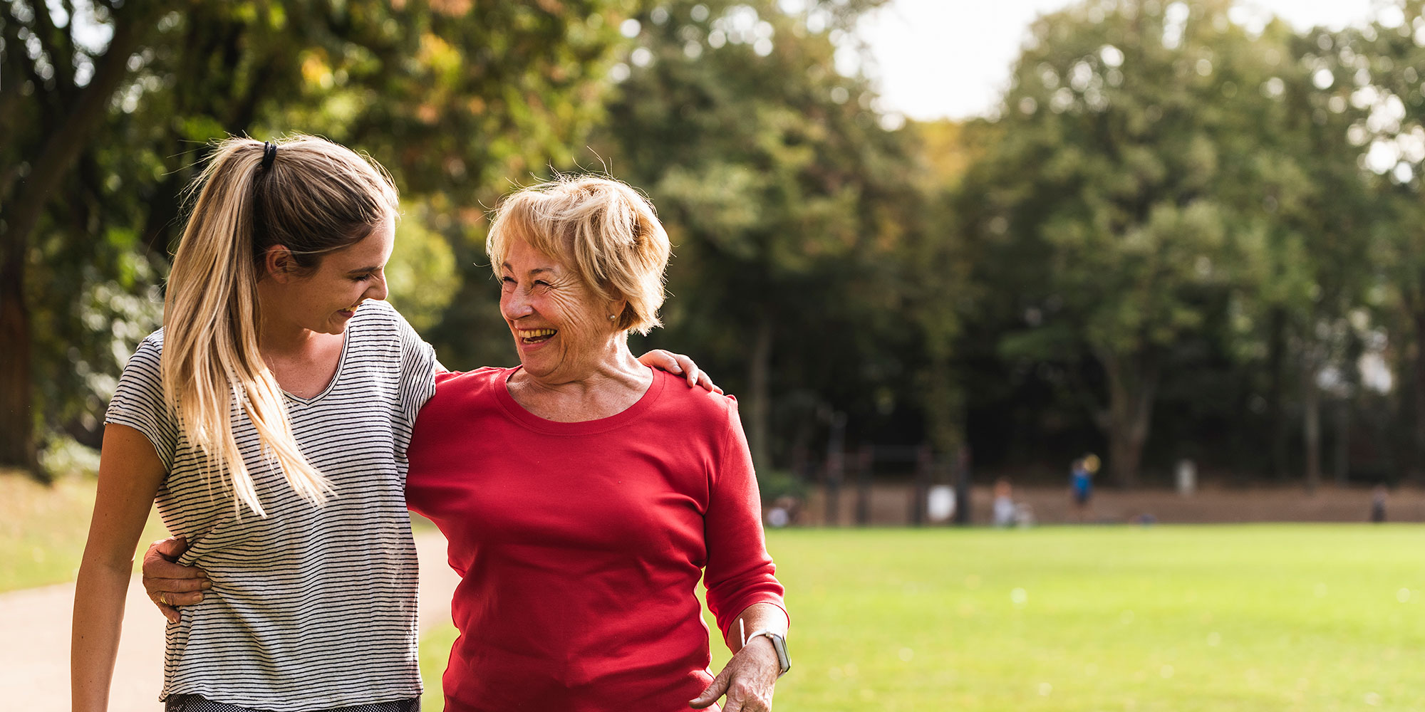 A woman and her grandmother stroll happily through a park