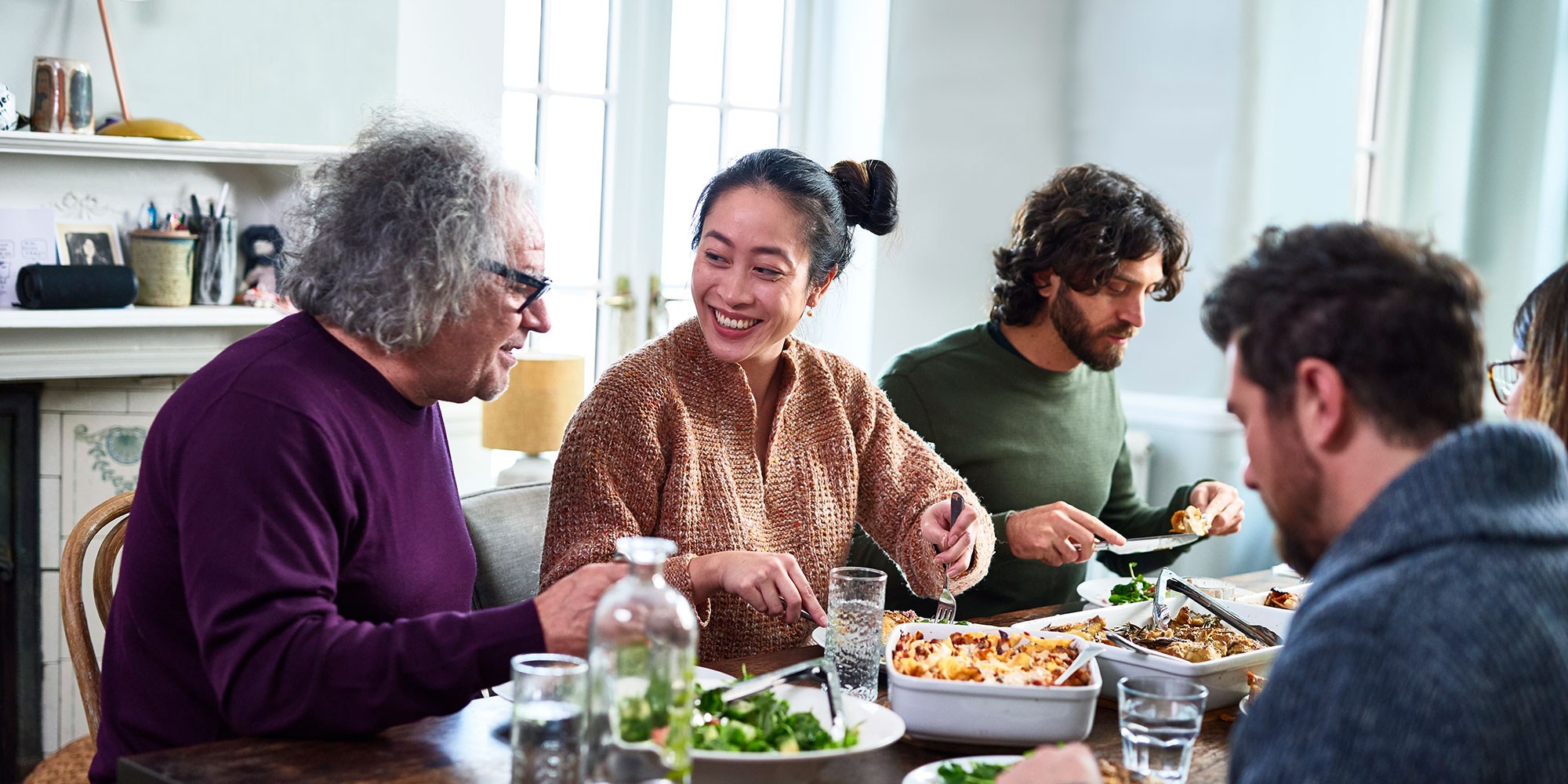 A group of adults enjoys each other's company over dinner with salad and lasagna being the main course